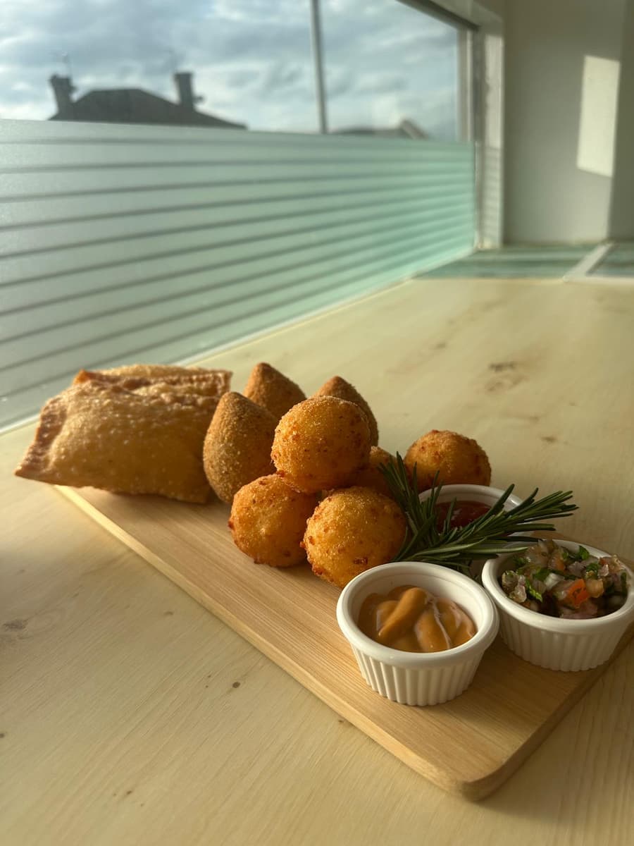 Pastel, coxinhas and cheese balls on a board by the window